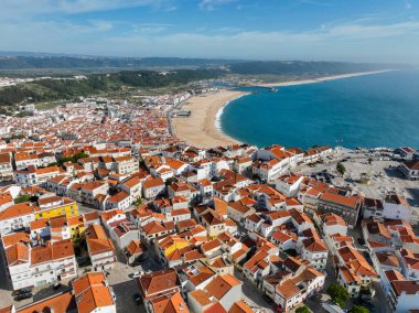Nazare çatılarının insansız hava aracı görüntüsü ve Atlantik Okyanusu boyunca Praia da Nazare plajı