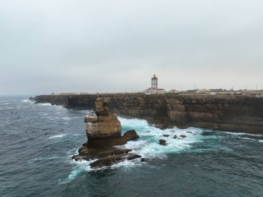Arka planda Cabo Carvoeiro Deniz feneri ile kaya yığını oluşumu