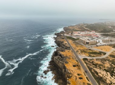 Portekiz 'in sahil yolu ve Cabo Carvoeiro yakınlarındaki uçurum kenarındaki binaları dramatik bir şekilde görüyor.