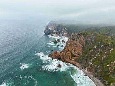 Portekiz 'deki pürüzlü kaya kayalıkları ve turkuaz okyanus kıyı manzarası