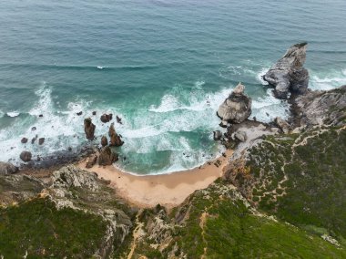 Praia da Ursa 'nın engebeli kayalar ve turkuaz dalgalarla drone görüntüsü
