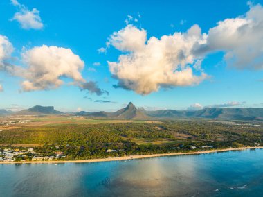 Flic en Flac plajının havadan görünüşü evler ve ormanlarla dolu, arkasında dramatik dağlar var.