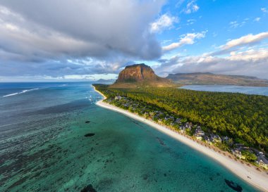 Le Morne, Mauritius 'ta yemyeşil orman ve ikonik dağ manzaralı bir kıyı şeridi ve göl.