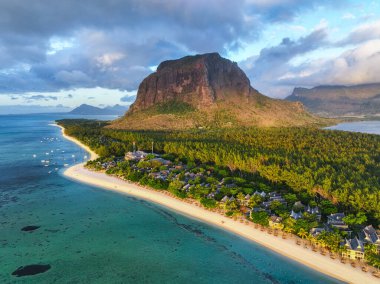 Sabah güneşi sahilin kıvrımlarını aydınlatır ve Mauritius, Le Morne yarımadasını çevreleyen sakin denizi aydınlatır.