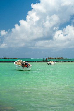 İki küçük tekne kristal berraklığında turkuaz sularda, uzak bir resif ve bulutlu gökyüzünde demirlediler.