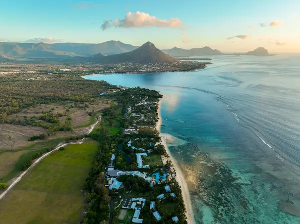 Yumuşak akşam ışığında kıyı şeridi, dağlar ve okyanusun geniş hava manzarası