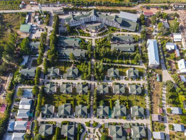Balykchy, Kırgızistan - 12 Mayıs 2023: Sayısız kır evi, bir ana otel binası ve iyi korunmuş yeşil alanlar içeren tepeden tırnağa bir tatil köyü manzarası