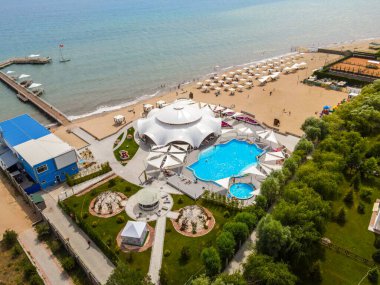 Balykchy, Kırgızistan - 12 Mayıs 2023: Yüzme havuzu, şezlonglar, plaj şemsiyeleri ve iskelesi olan büyük bir tatil köyünün havadan çekilmiş fotoğrafı