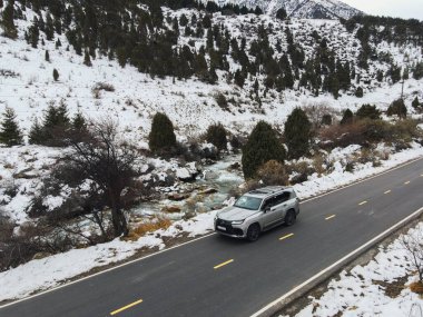 Bishkek, Kyrgyzstan - December 12, 2024: The new Lexus LX luxury SUV is seen driving on a paved road alongside a river in a snowy mountain landscape