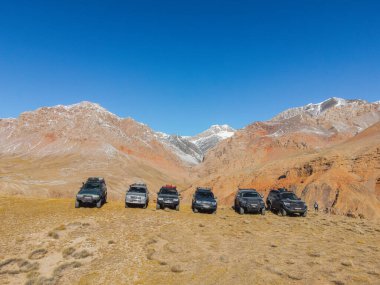 Naryn, Kyrgyzstan - December 12, 2023: A fleet of six Toyota Land Cruiser and Prado SUVs lined up on a ridge during a tour of the Naryn region's colorful mountains