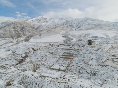 Kırgızistan 'da terk edilmiş bir Sovyet hayalet kasabası olan Enilchek' teki karla kaplı bir tepedeki eski bir madencilik operasyonunun çürüyen beton yapılarının hava görüntüsü.
