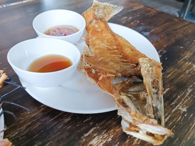 Tahta bir masada balık soslu kızarmış levrek.