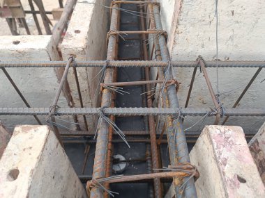Close-up view of reinforced concrete beam rebar arrangement at construction site. Steel reinforcement bars tied with wire, ready for concrete pouring. Structural building foundation framework