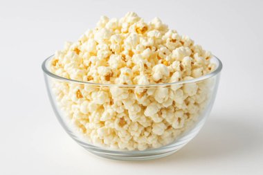 Cam kase beyaz arka planda kabarık patlamış mısırla dolu. Klasik film atıştırmalığı, hafif ve çıtır çıtır.