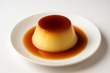 Beyaz tabakta servis edilen klasik karamel pudingi. Karamel soslu yumuşak ve kremalı tatlı..