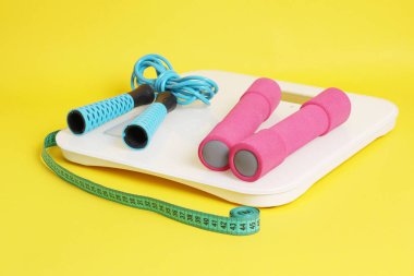 Pullar, ip atlama, metre, sarı arkaplanda halterler.