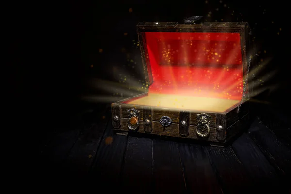 Sihirli ışıkları çıkan eski antika ahşap hazine kutusu. Kazanan tema koyu arkaplan.