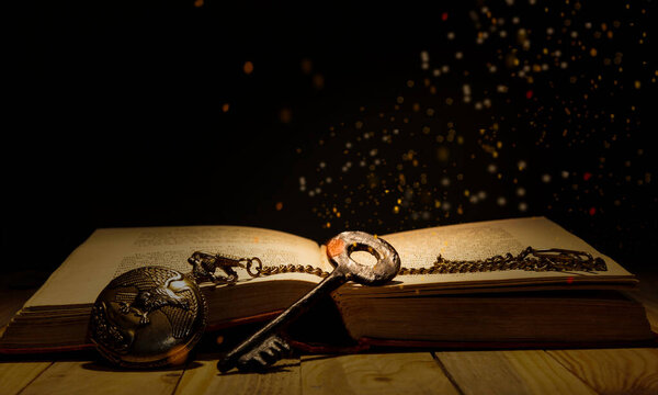 Knowledge is power theme with old key and antique book with magic lights coming down.