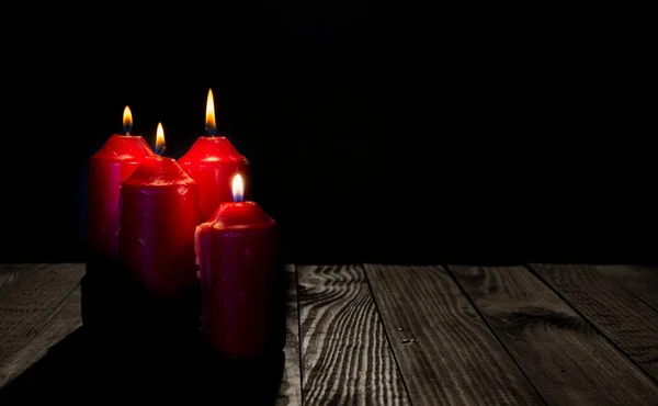 Four advent theme candles on dark wood table.