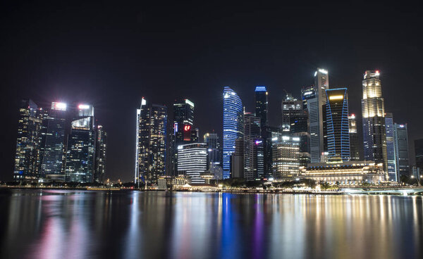 Singapore business district skyscrapers at night with reflection in water.
