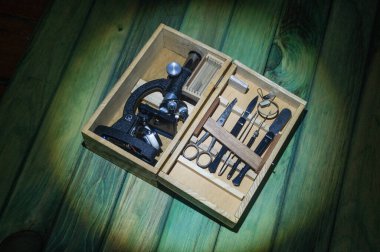 Yeşil panoda ekipmanları olan antika mikroskop kutusu.