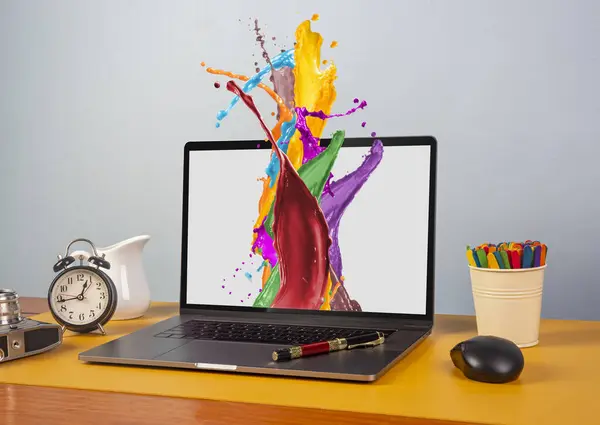 Dizüstü bilgisayarından boya sıçrayan grafik tasarımcı masası.