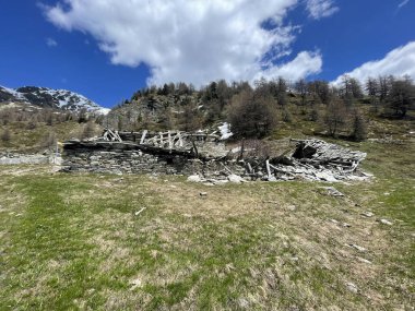 İtalyan Alpleri 'nin hava manzarası, arka planda karla kaplı tepeler, mavi gökyüzü ve beyaz bulutlar.