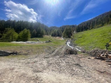 İtalyan Alpleri 'nin hava manzarası, arka planda karla kaplı tepeler, mavi gökyüzü ve beyaz bulutlar.