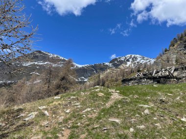 İtalyan Alpleri 'nin hava manzarası, arka planda karla kaplı tepeler, mavi gökyüzü ve beyaz bulutlar.