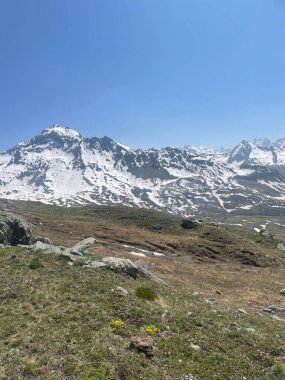İtalyan Alpleri 'nin hava manzarası, arka planda karla kaplı tepeler, mavi gökyüzü ve beyaz bulutlar.