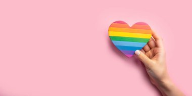 Soyut arkaplan. LGBTQ kavramı, gökkuşağı kağıdından kalbi tutan bir el ile eşit sevgi ve özgürlüğü temsil eder. pembe, kabullenme, eşitliği anlama.