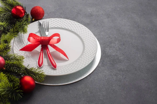 圣诞桌上摆设 包括一个白色盘子和用弓子捆扎的餐具 侧面视图 深色背景 有复制空间 — 图库照片