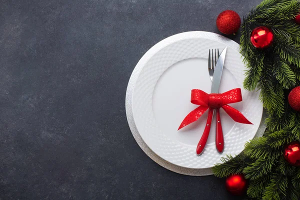 白い皿と弓で結ばれた刃物で構成されたクリスマステーブルの設定 トップ表示 コピースペース付きの暗い背景に — ストック写真