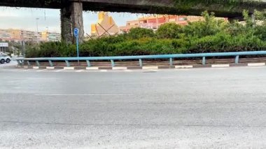 Alicante, İspanya - 25 Nisan 2025: Şehir kavşağında sakin bir sabah yolculuğu. Bölge yol kenarındaki yemyeşil santrallere ve uzaktaki binalara sahip ve huzurlu bir yer oluşturuyor.