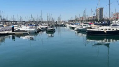 Alicante, İspanya - 29 Mayıs 2025: Çeşitli teknelerle dolu sakin bir marina açık mavi gökyüzünün altında dinleniyor. Durgun su, güneşli öğleden sonranın deniz aktivitelerini yansıtır..