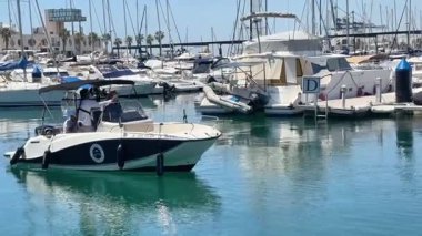 Alicante, İspanya - 29 Mayıs 2025: Parlak güneş altında sayısız yat ve yelkenliyle dolu canlı bir marinada sorunsuzca yol alan bir tekne. Köpüklü su etrafındaki güzelliği yansıtır..