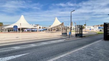 Alicante, İspanya - 3 Haziran 2025: Siyah konteynırlı ağır yük kamyonu şehir ortamında çağdaş bir binanın önünden geçiyor