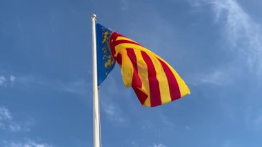 Alicante, İspanya - 3 Haziran 2025: Valencia bayrağı parlak mavi gökyüzüne karşı belirgin bir şekilde sergileniyor, zengin renkleri ve kültürel önemi vurgulanıyor