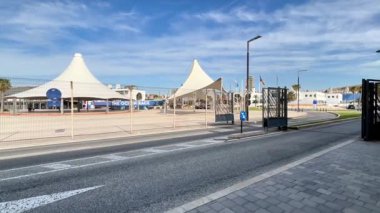 Alicante, İspanya - 3 Haziran 2025: Siyah konteynırlı ağır yük kamyonu şehir ortamında çağdaş bir binanın önünden geçiyor