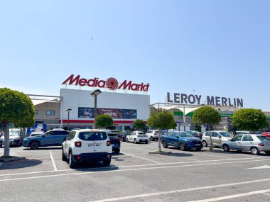 Alicante, İspanya - 18 Haziran 2025: Medya Markt ve Leroy Merlin mağazaları açık mavi gökyüzü altında arabalarla dolu kalabalık bir otoparkta görülebilir
