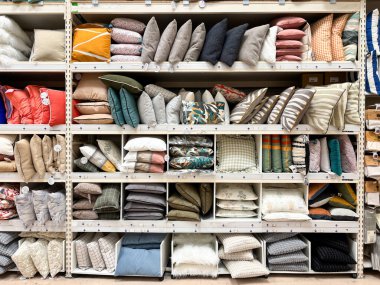 Alicante, İspanya - 18 Haziran 2025: Bir ev dekorasyonu mağazasında raflarda çeşitli renkler, desenler ve şık iç dekorasyonlar içeren dekoratif yastıklar