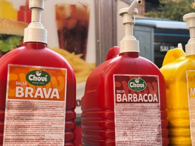 Alicante, İspanya - 24 Haziran 2025: Kırmızı ve sarı renkte Chovi salsa şişeleri bir gıda standında belirgin bir şekilde sergilenmektedir, yemekler için mükemmeldir