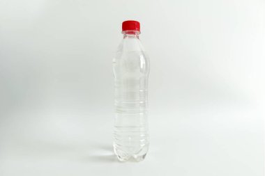 Sade arka planda kırmızı kapaklı su dolu temiz plastik şişe