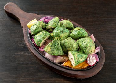 Pudina Tikka 'nın yakın çekimi, yoğurt, nane ve baharatla marine edilmiş geleneksel Hint tavuk parçaları, soğanla birlikte cızırdayan bir tabakta servis ediliyor, koyu bir ahşap arka planda limon dilimi ile izole edilmiş..