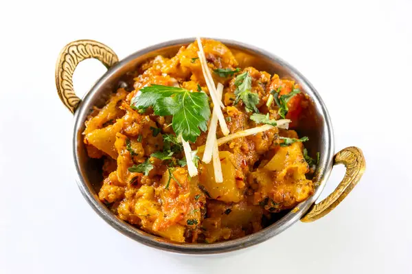 Aloo Gobi Masala geleneksel Hint mutfağı taze karnabahar, patates, soğan sosu ve domatesle pişirilmiş beyaz bir arka planda yakından ve izole edilmiş baharatlarla.