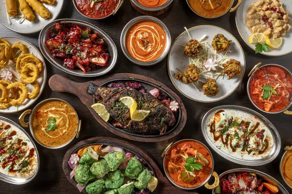 Hint yemeklerinin tipik kompozisyonu köri, naan ve pirinç gibi, koyu ahşap bir masa üzerinde sergilenen sıcak otlatma ışığı, canlı baharatlar ve rustik kaselerde süslemeler.