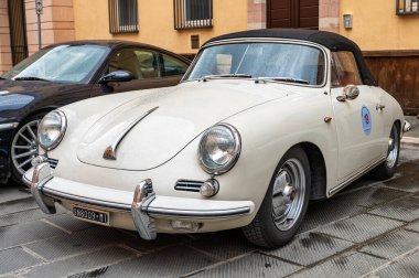 Klasik bir Porsche 356 C Cabriolet, siyah kapaklı beyaz, Foligno 'nun tarihi merkezine park edilmiş Porsche sahipleri ve koleksiyoncular rallisi sırasında, klasik bir zarafet sergiliyor. Foligno, İtalya, 18 Mayıs 2025.