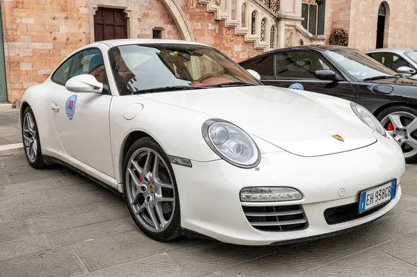 Porsche sahiplerinin ve koleksiyoncuların mitingi sırasında Foligno 'nun tarihi merkezine park etmiş beyaz bir Porsche 911 Carrera (9997.2), taştan bir zemine karşı lüks ve otomotiv tutkusu sergiliyor. Foligno, İtalya, 18 Mayıs 2025.