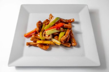 Nuoc mama soslu karamelize domuz eti, Asya mutfağı tarifi, beyaz arka planlı bir tabakta servis ediliyor. Zengin, parlak bir fotoğraf, Vietnam ve Asya mutfağı teması için mükemmel.. 