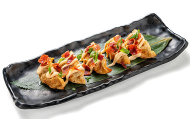Beyaz arka planda servis edilen mayonez ve pastırmalı gevrek gyoza seramik tepsisinin yakından görüntüsü. Çin mutfağını modern bir kıvrımla harmanlayan lezzetli bir Asya yemeği. Temiz ve asgari estetik içeriyor.